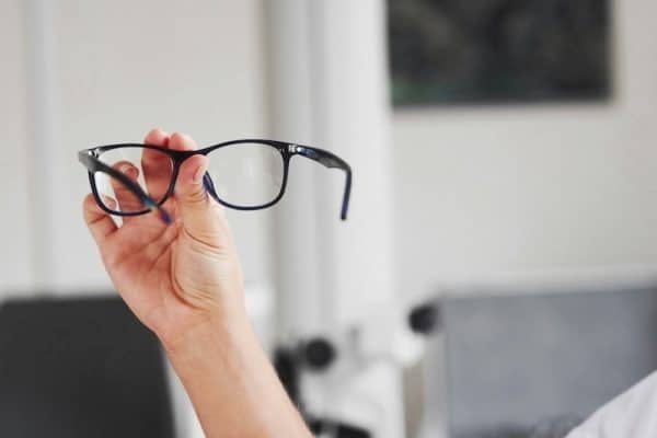 Arm holding up a pair of eyeglasses.