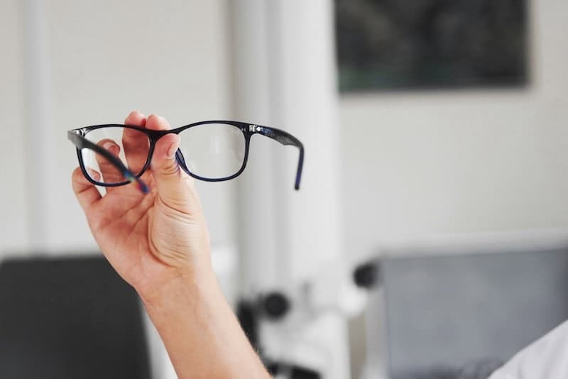 Arm holding up a pair of eyeglasses.