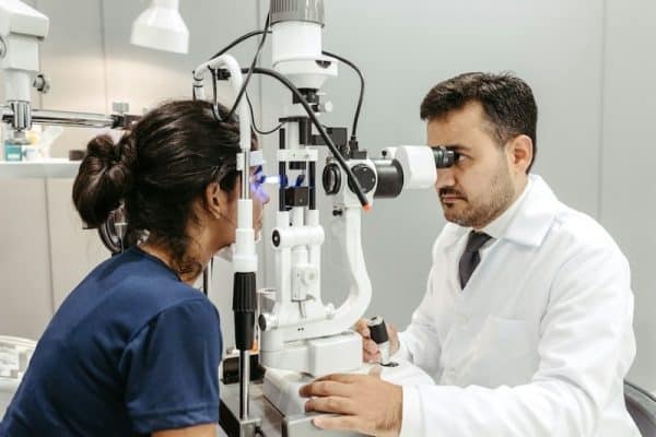 Male eye doctor examining the eyes of a female patient.