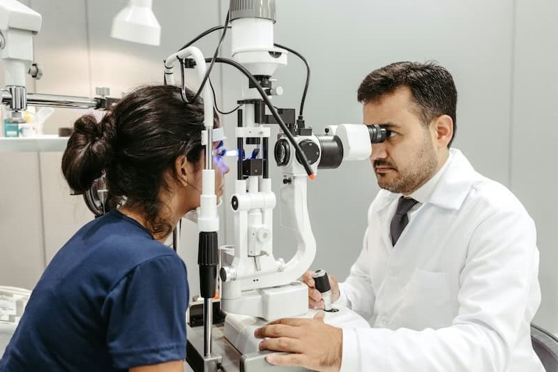 Male eye doctor examining the eyes of a female patient.
